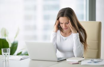 stressed woman with headache at her workplace