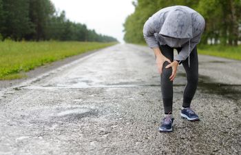 the runner is holding his sore knee