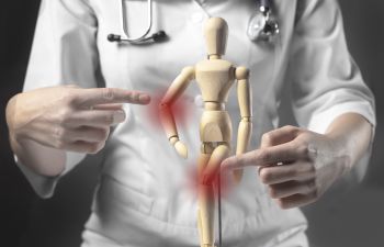 A doctor presenting inflammmed joints on a wooden mannequin.