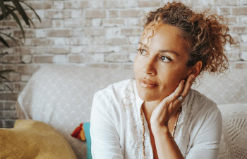 pensive woman in tight curly hair sitting on the couch