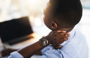 Office, stress and black man at laptop with neck pain, fatigue and business burnout from back. Posture, ergonomics and tired businessman with muscle cramps, injury and overworked at digital agency