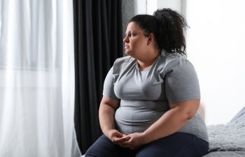 Depressed overweight woman on bed at home